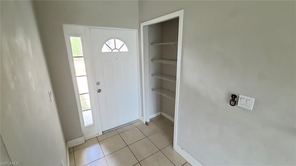 Entryway featuring tile flooring, a white paneled door with a sunburst-patterned transom, and a side light window