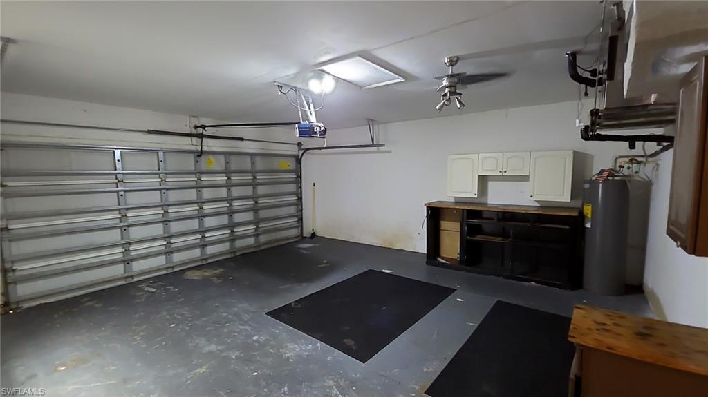 Spacious garage featuring a sectional overhead door with automatic opener, built-in cabinetry, a water heater, and overhead lighting