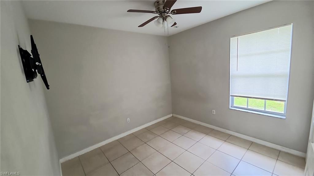 Neutral wall paint with tile flooring, a ceiling fan, and a window featuring horizontal blinds