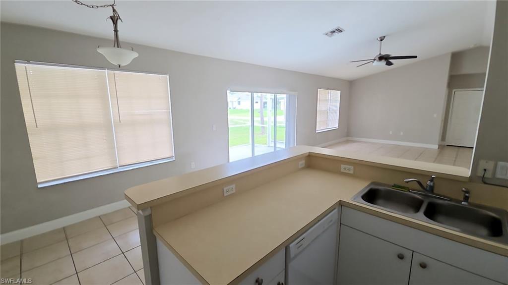 Kitchen with a double basin stainless steel sink, light-toned countertops, and white cabinetry