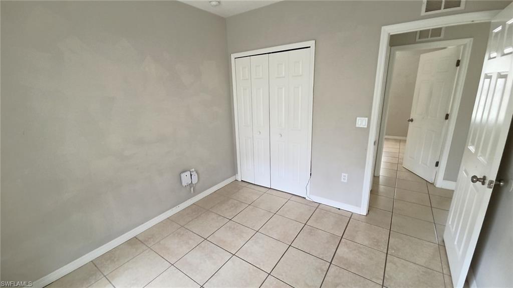 Room featuring neutral wall tones, tile flooring, and a bifold door closet