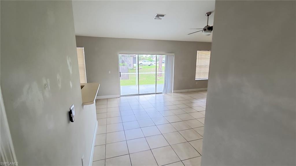 Open-concept living space with tile flooring throughout, a ceiling fan, and sliding glass doors leading to an outdoor area