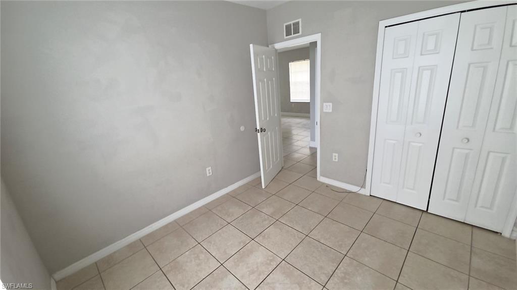 Neutral-toned tiled flooring throughout, complemented by light gray wall finishes and white baseboards