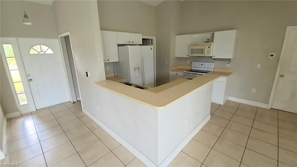 Kitchen featuring white cabinetry, light countertops, and tile flooring