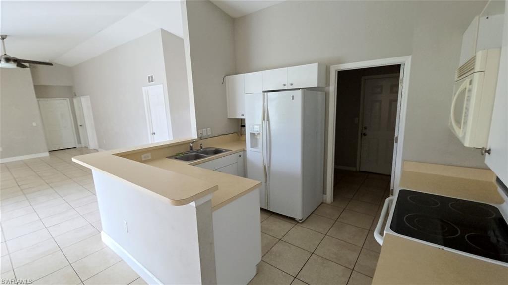 Kitchen featuring an L-shaped counter, white cabinetry, and tile flooring