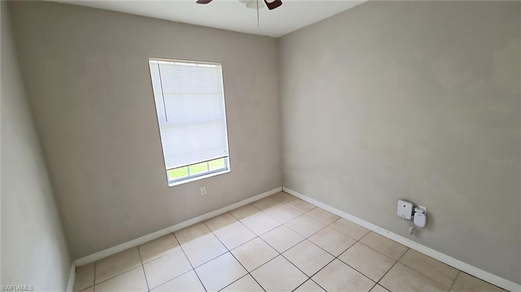 Neutral-toned interior room featuring tile flooring, a window with horizontal blinds, and a ceiling fan