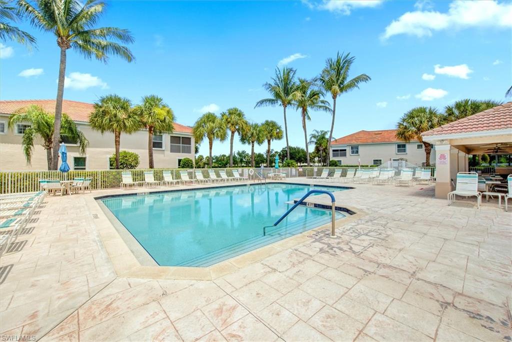 Resort-style swimming pool featuring a patterned concrete deck, integrated steps, and a handrail