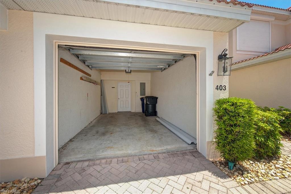 One-car extra long garage with concrete flooring, stucco walls, and a white entry door