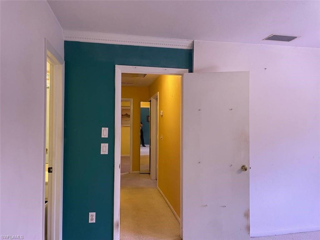 Hallway with a teal accent wall, white crown molding, and white trim