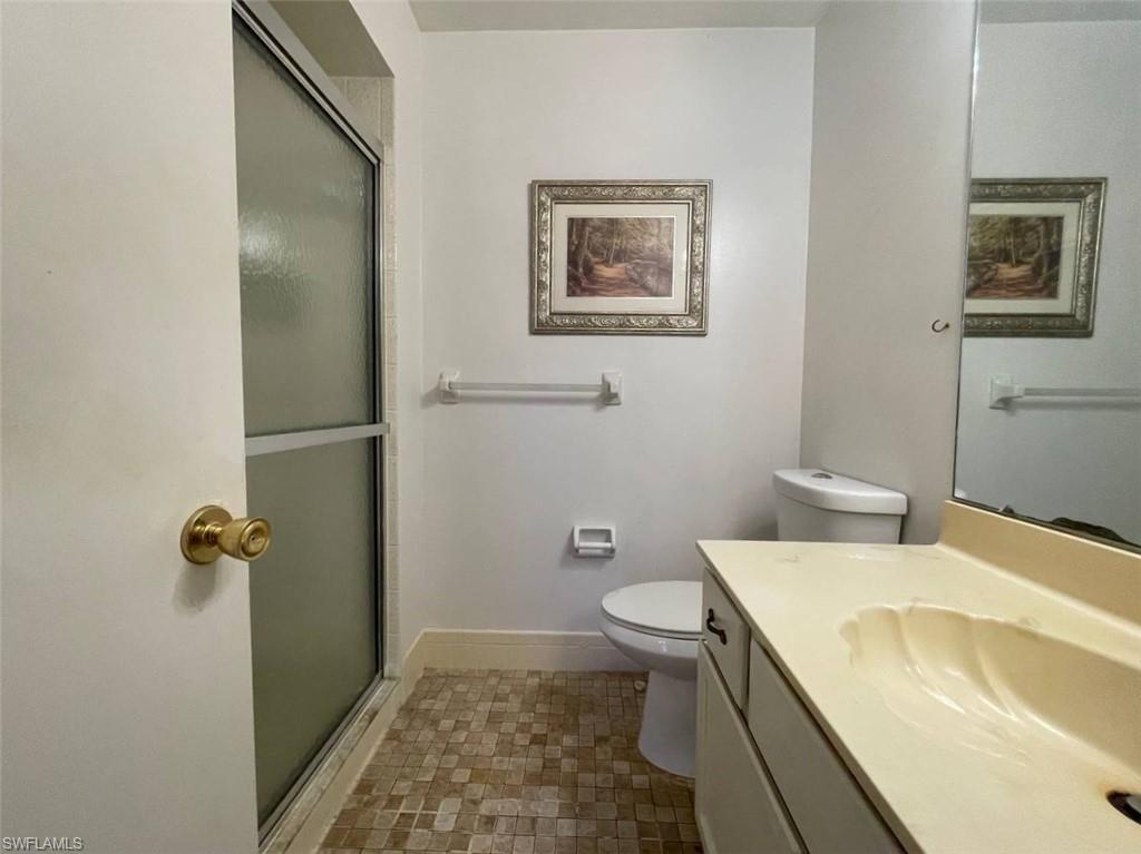 Bathroom featuring a frosted glass shower enclosure, mosaic floor tiling, and a vanity with an integrated sink