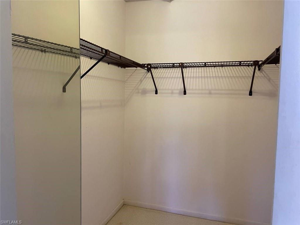 Corner closet featuring a built-in wire shelving system, integrated hanging rods, and light-toned wall finishes