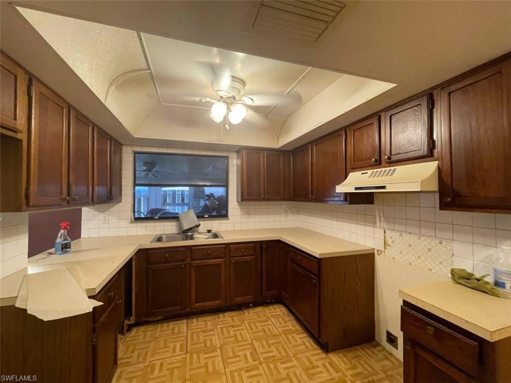 U-shaped kitchen featuring wood cabinetry, light-toned countertops, and a tile backsplash