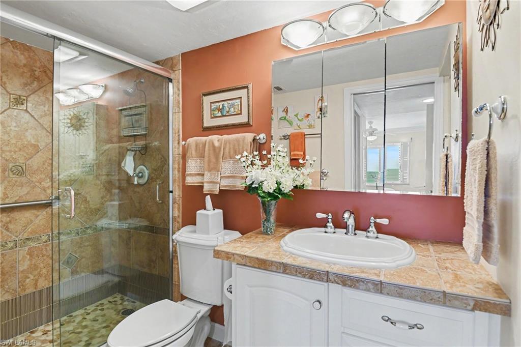 UPDATED PRIMARY SUITE BATH.  FULL-HEIGHT TILED SHOWER WITH FRAMELESS GLASS SLIDING DOORS.