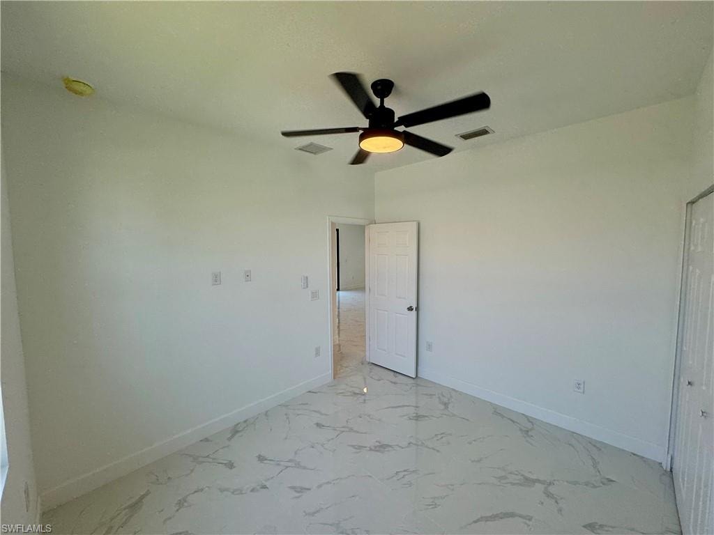 Empty room with ceiling fan and light tile floors
