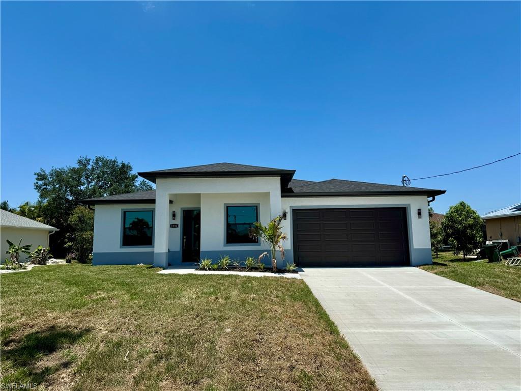 View of front of home with a garage and a front lawn