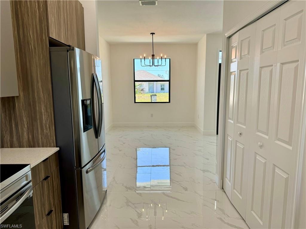 Kitchen featuring a notable chandelier, hanging light fixtures, stainless steel fridge with ice dispenser, and light tile floors