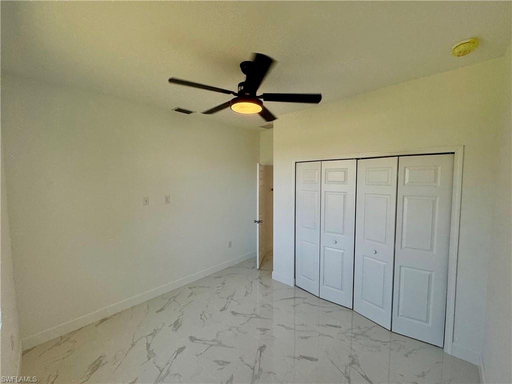 Unfurnished bedroom featuring ceiling fan, a closet, and light tile floors