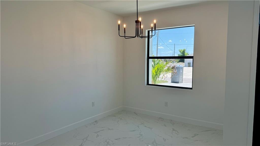 Empty room featuring a notable chandelier and tile flooring