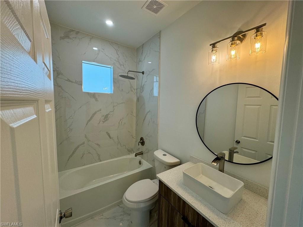Full bathroom with toilet, vanity, and tiled shower / bath