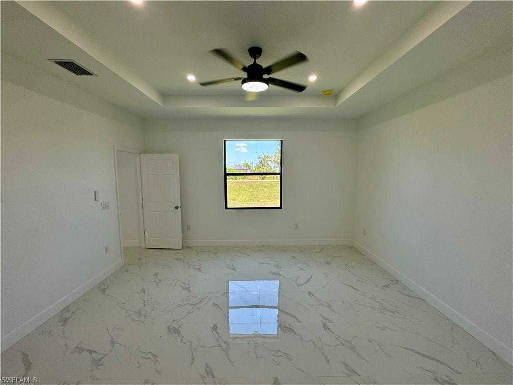 Unfurnished room with ceiling fan, a raised ceiling, and light tile floors