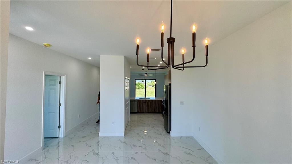 Unfurnished dining area with an inviting chandelier and light tile floors