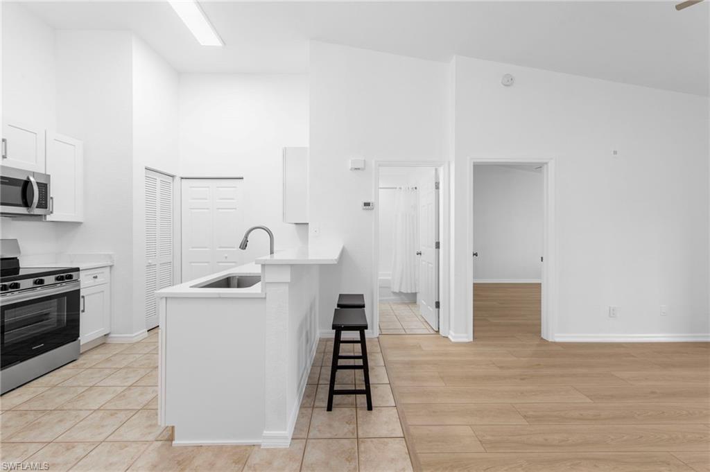 Kitchen featuring white cabinetry, stainless steel appliances, and a breakfast bar with seating