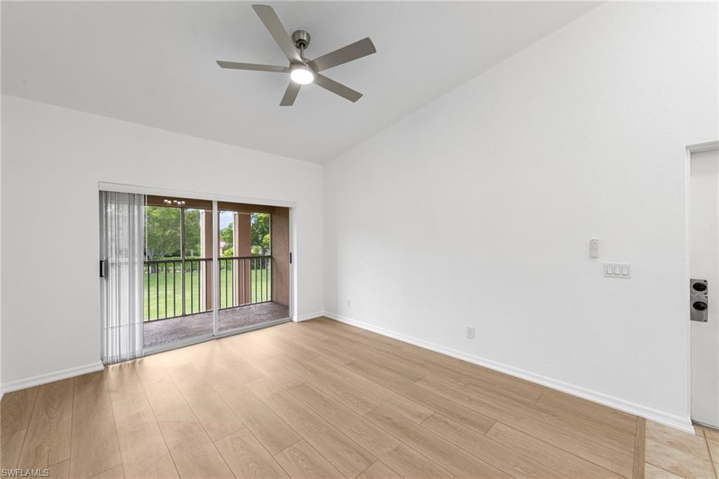 Bright interior featuring wood-finish flooring, a ceiling fan with integrated lighting, and a vaulted ceiling