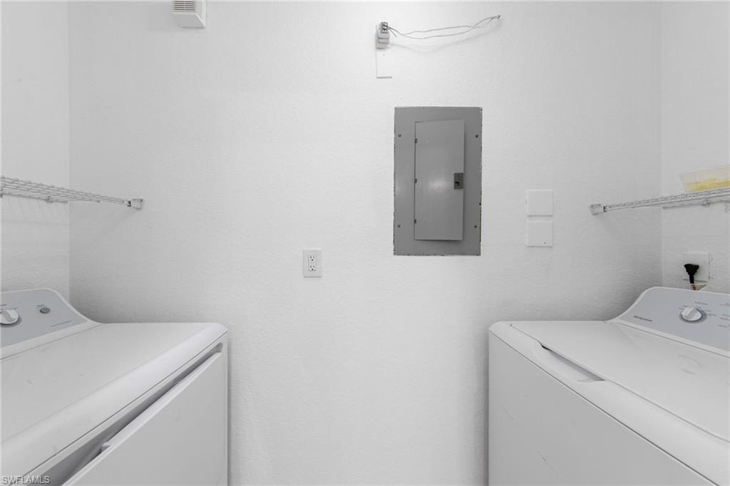Dedicated laundry area featuring a white textured wall finish, a built-in electrical panel, and overhead wire shelving