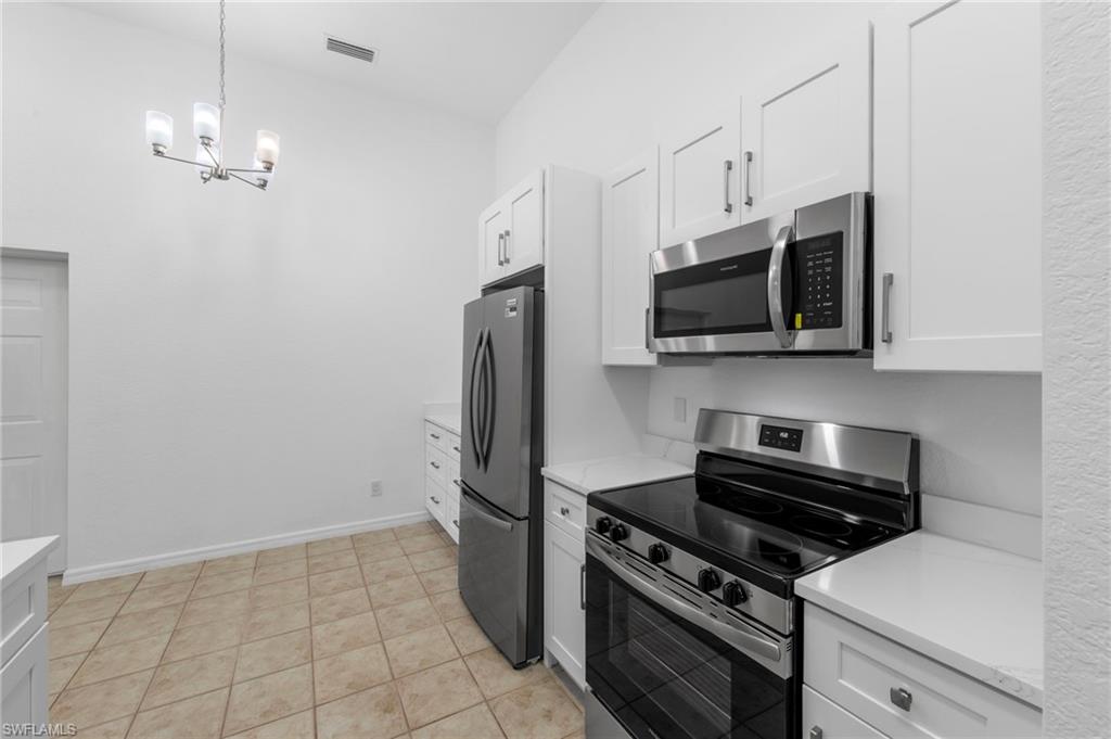 Contemporary kitchen featuring stainless steel appliances, white shaker cabinetry, white countertops, a tile backsplash, and ceramic tile flooring
