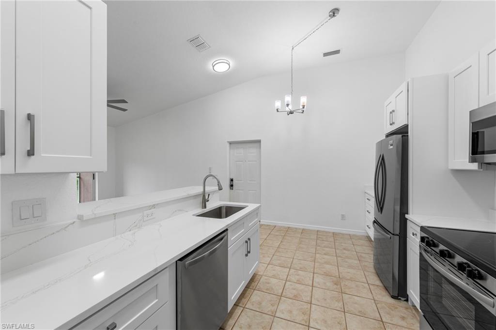 Bright kitchen featuring white shaker cabinetry, stainless steel appliances, and a peninsula with a stainless steel sink