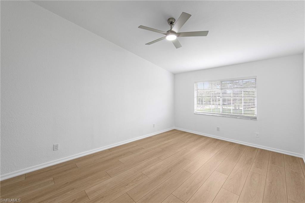 Spacious room featuring wood-finish flooring, white baseboards, and a neutral wall palette