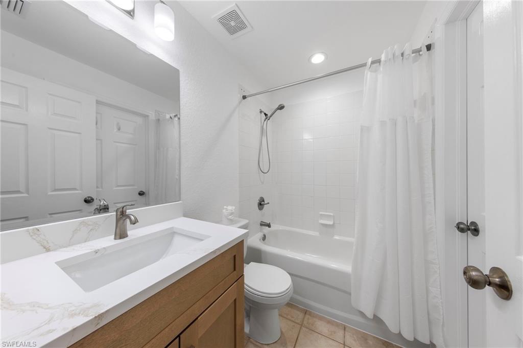 Bathroom vanity featuring a rectangular undermount sink, a stone-finish countertop, and a brushed nickel faucet