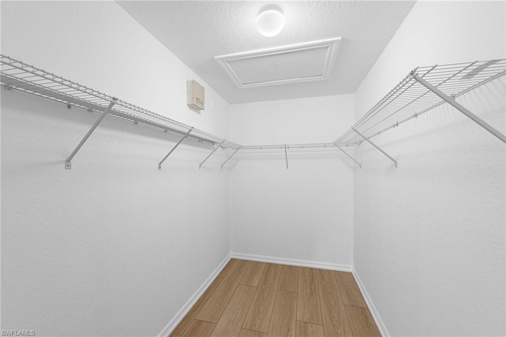 Walk-in closet featuring wood-finish flooring, white baseboards, and white wire shelving