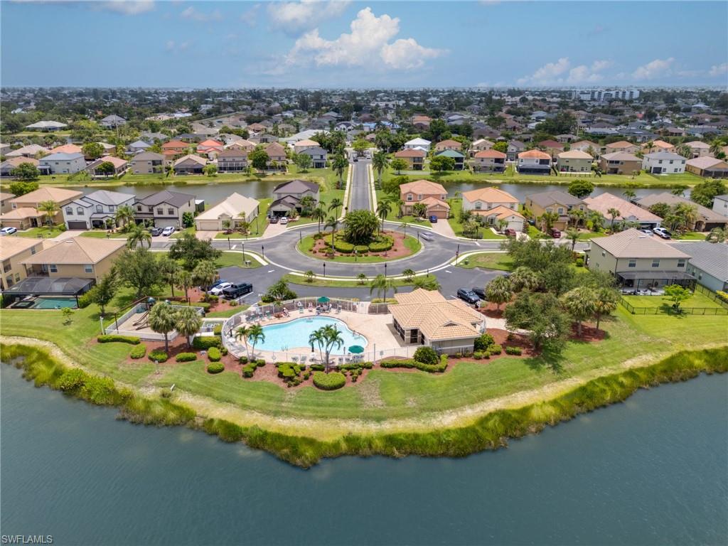 Community pool and clubhouse with surrounding residential properties, featuring a central roundabout, mature trees, and waterfront access