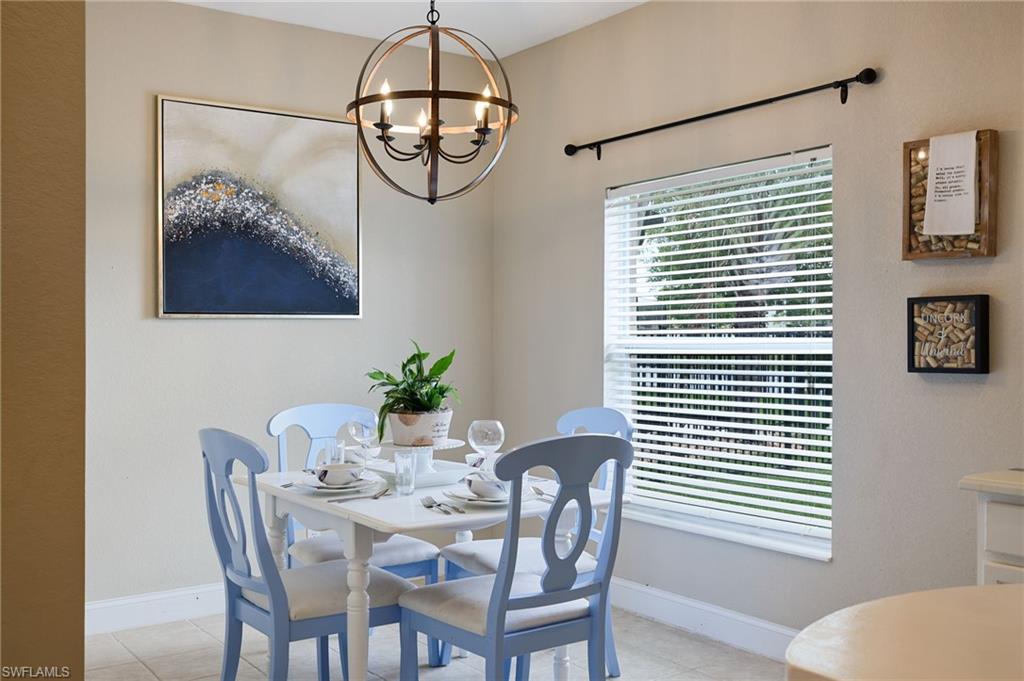 Dining space with a multi-light orb chandelier, window with horizontal blinds, and neutral-toned walls