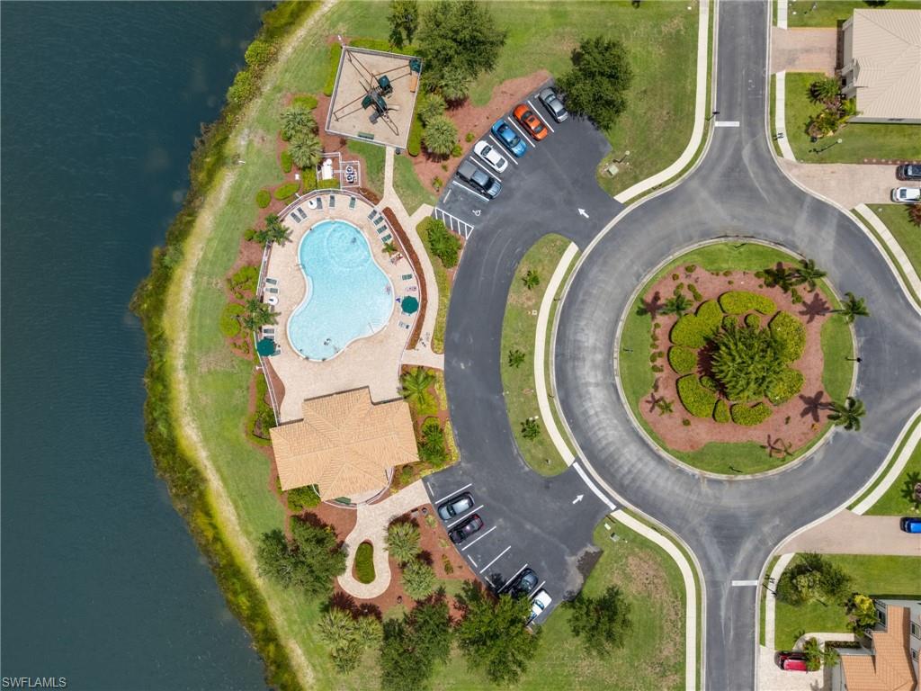 Recreational area featuring a large freeform swimming pool, adjacent deck with lounge seating, covered building with a tile roof, and a children's play structure