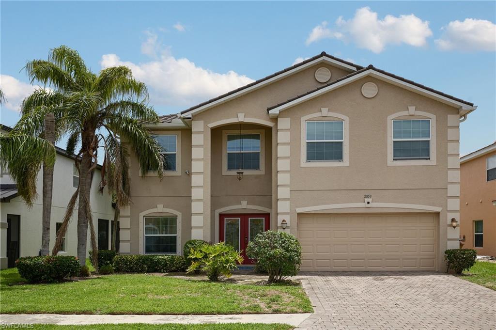Two-story stucco exterior featuring a gabled roof, prominent entryway with red double doors, and an integrated two-car garage
