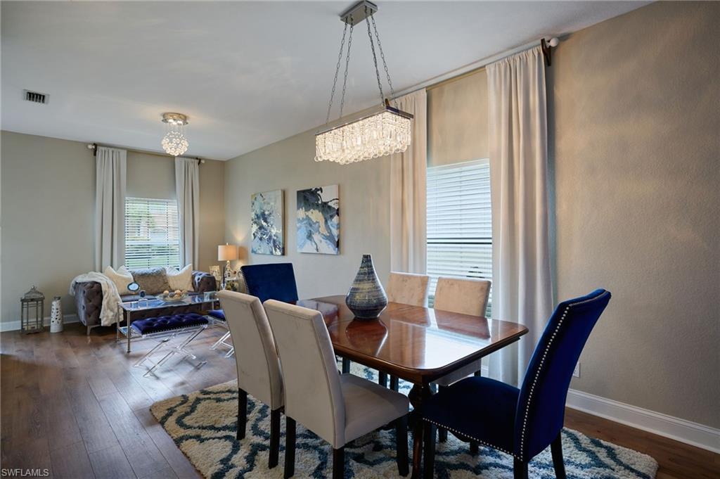 Open-concept living area with wood-finish flooring, neutral wall tones, and white window blinds