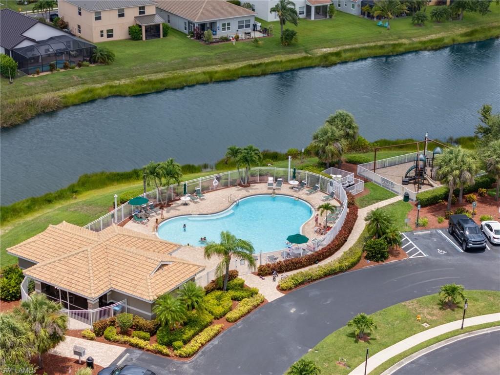 Curved swimming pool with ample deck space, a screened pavilion featuring a tiled roof, a dedicated children's play area, and surrounding lush landscaping