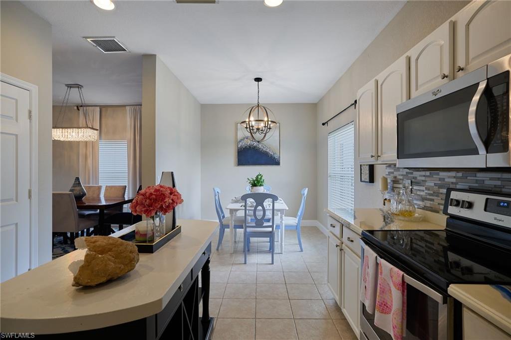Contemporary kitchen featuring stainless steel appliances, a mosaic tile backsplash, and light-toned cabinetry