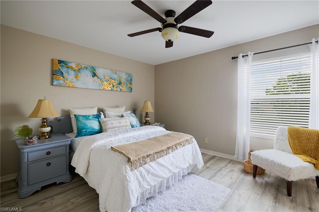 Bedroom featuring light gray walls, wood-finish flooring, a ceiling fan with light fixture, and a window with blinds