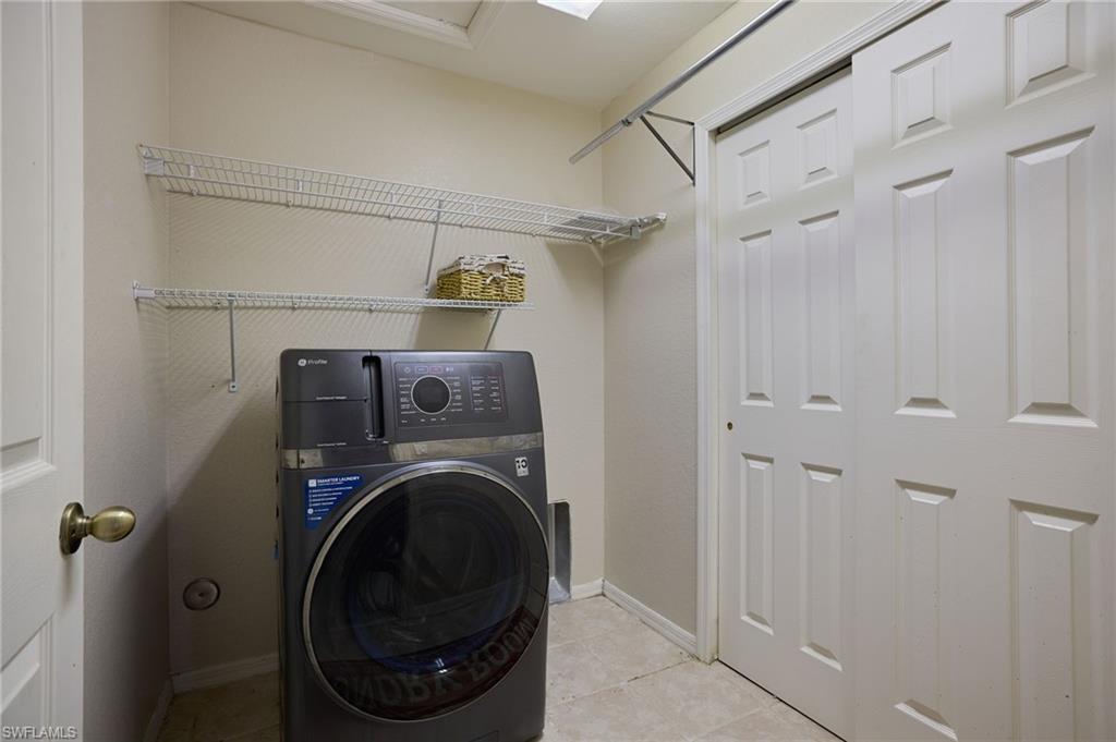 Laundry area featuring light-toned walls, tile flooring, and white wire shelving