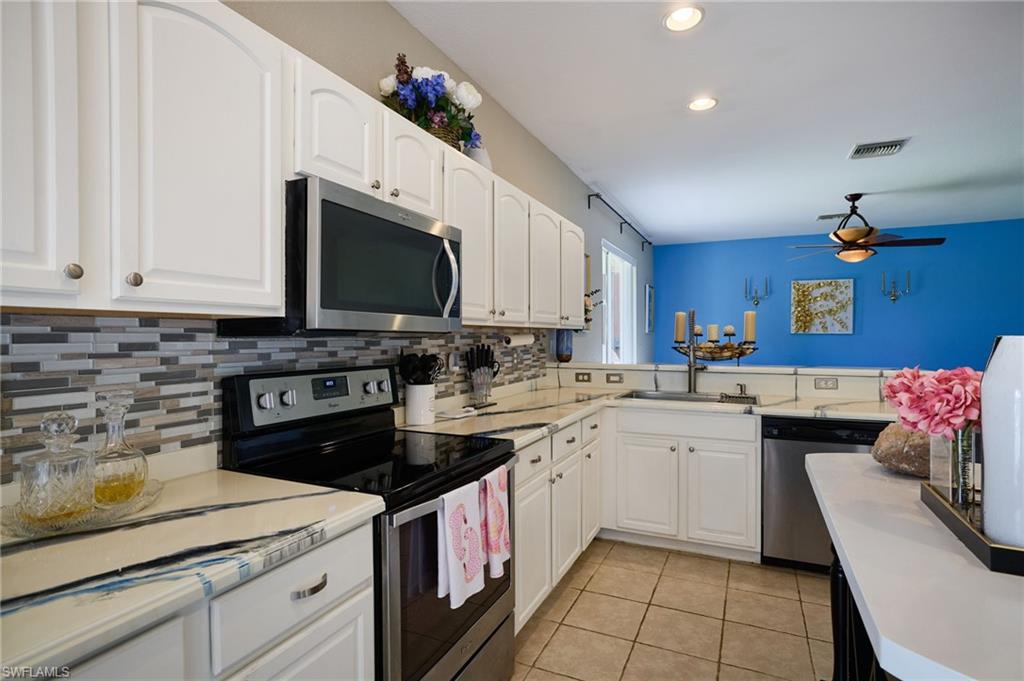 Kitchen featuring white cabinetry with brushed nickel hardware, a tile backsplash, and light-toned countertops