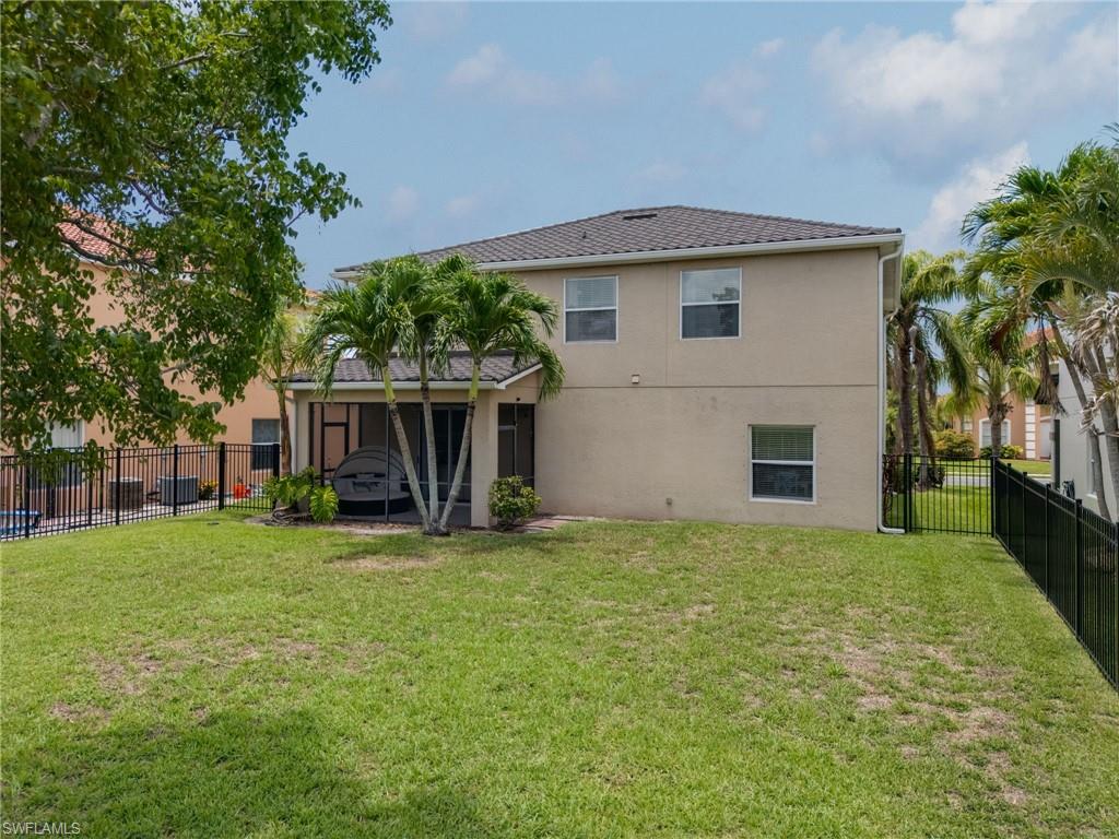 Expansive backyard featuring a manicured lawn, a two-story stucco exterior, a tiled roof, and a screened-in patio