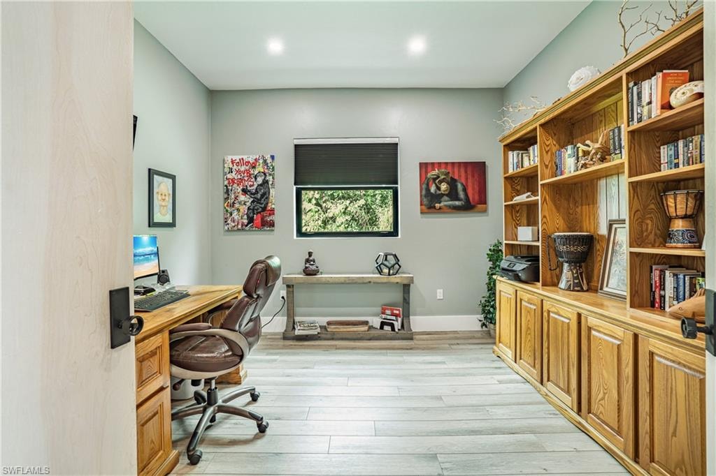 Dedicated room featuring extensive built-in wood cabinetry and shelving, recessed lighting, and wood-finish flooring