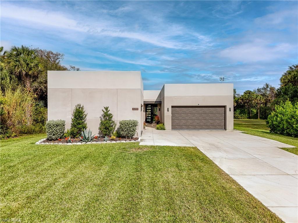 Contemporary stucco exterior with a textured garage door, concrete driveway, and a landscaped garden bed