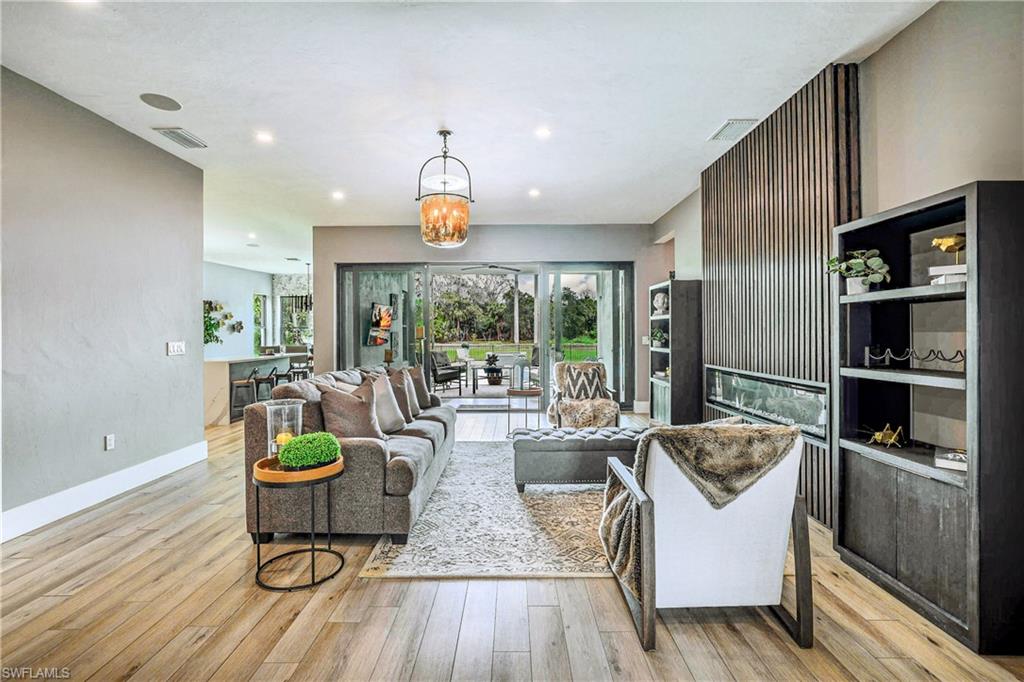 Expansive living area featuring light wood-finish flooring, recessed lighting, and a prominent accent wall with a linear fireplace