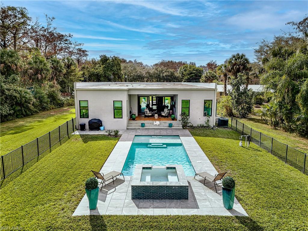 Contemporary residence featuring a rectangular pool with an integrated spa, expansive paver decking, and a spacious green lawn