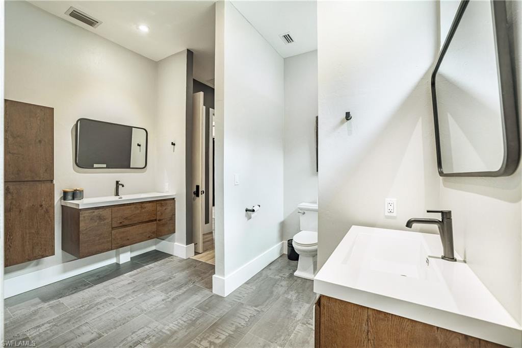 Modern bathroom featuring wood-finish flooring, white walls, and contemporary black fixtures