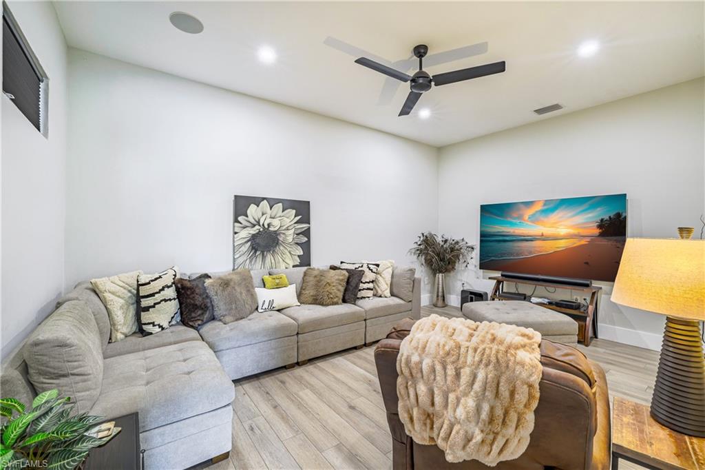 Spacious Media Room with built in surround sound speakers, featuring light wood-finish flooring, recessed lighting, and a modern ceiling fan